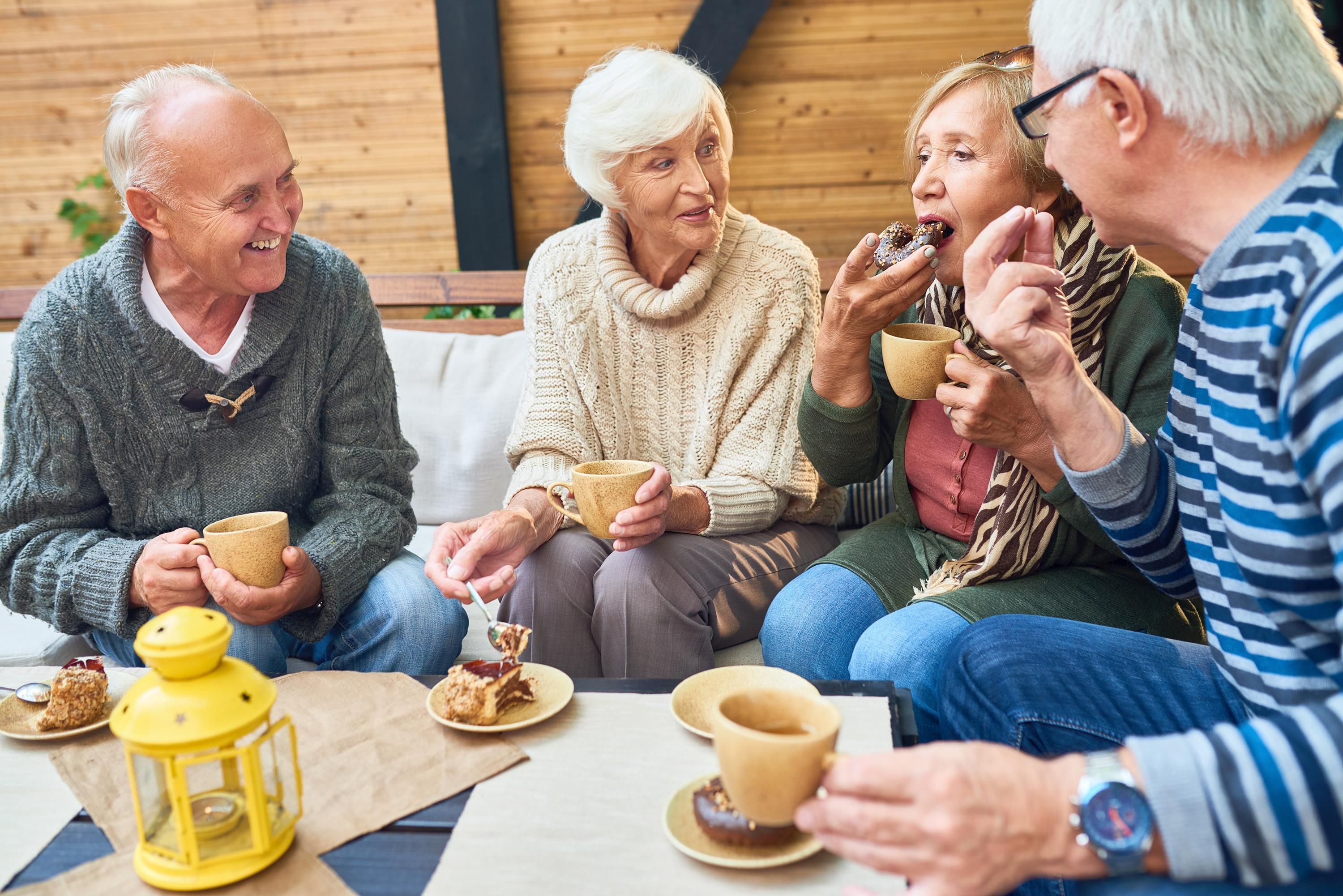 Vier ältere Menschen genießen in aller Ruhe Kaffee und Kuchen.